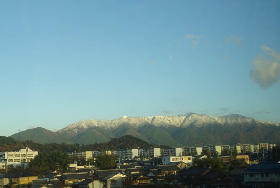 車窓から山への降雪が見える