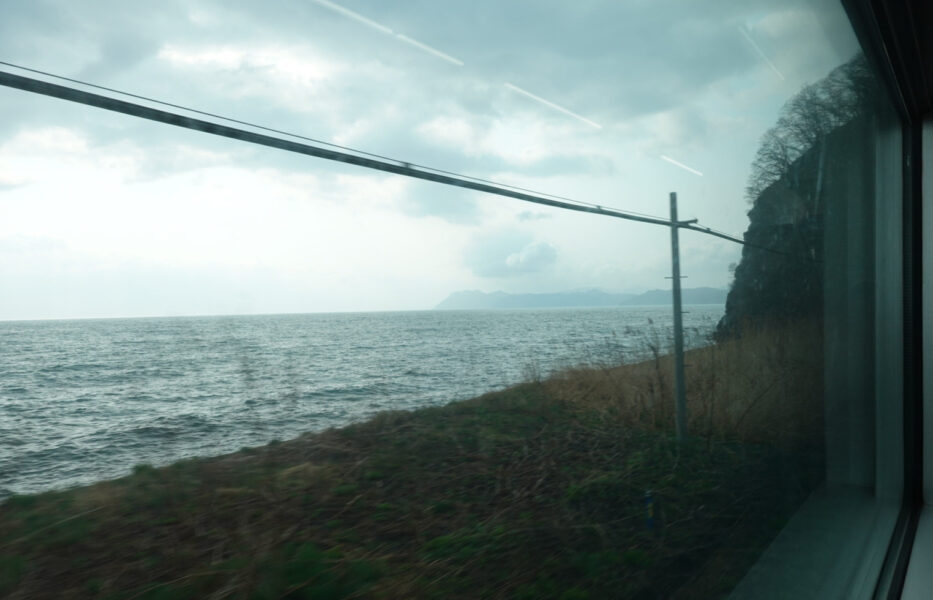 海の近くを走行する普通列車