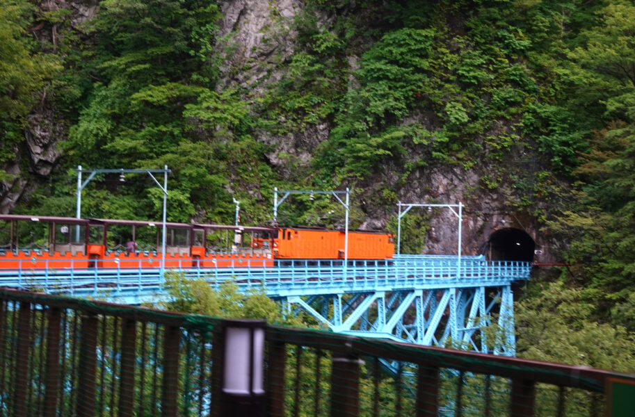 黒薙駅を出発し、後曳橋を渡る黒部峡谷鉄道の列車